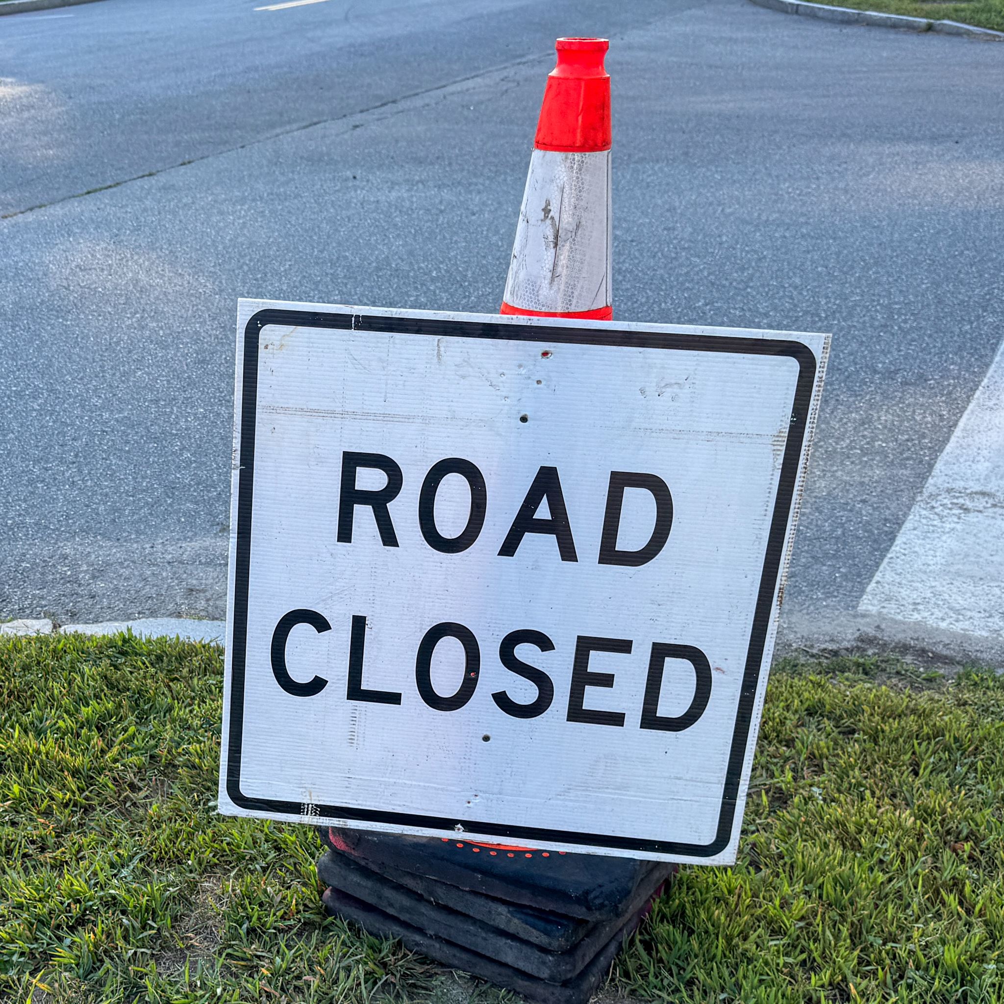 A sign against a traffic cone reading 