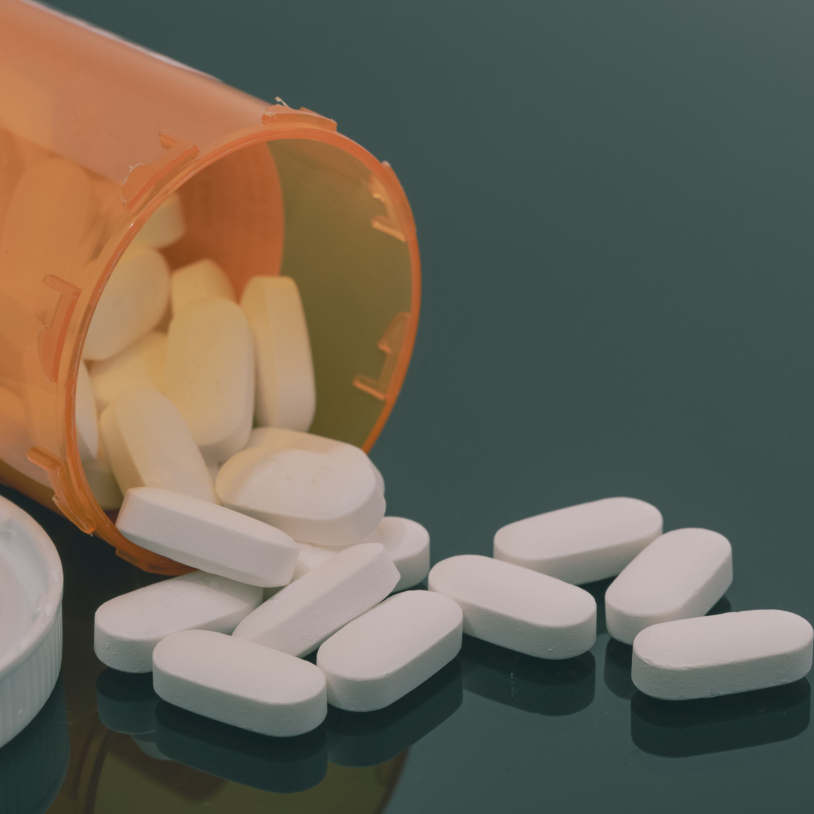 An emptied pill bottle and a pile of small white pills