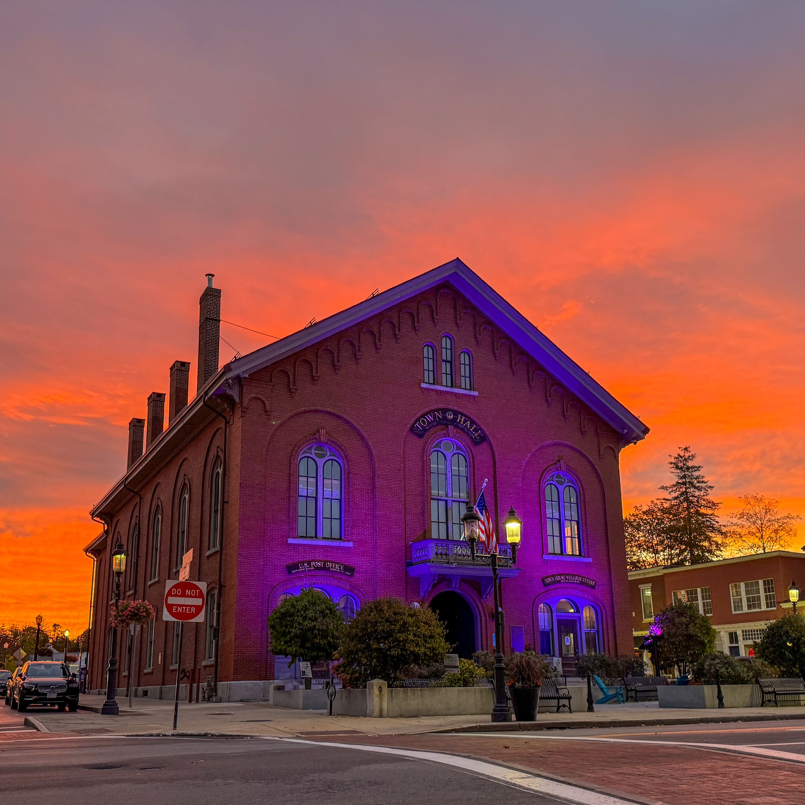 The front of Andover's Old Town Hall with a vibrant sunrise in the background. 